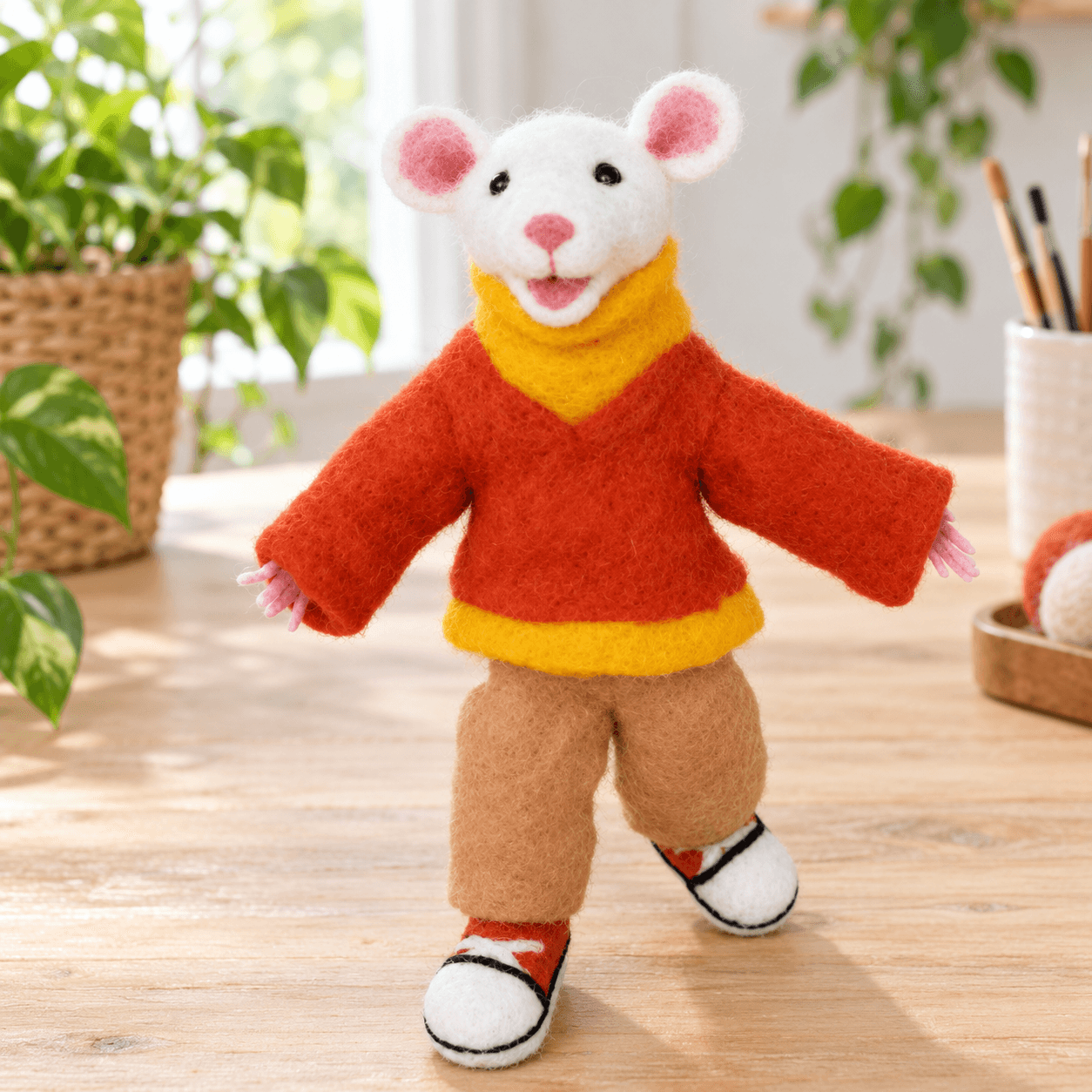 White needle felted hamster figure in a red and yellow sweater, tan trousers and sneakers, front view, standing