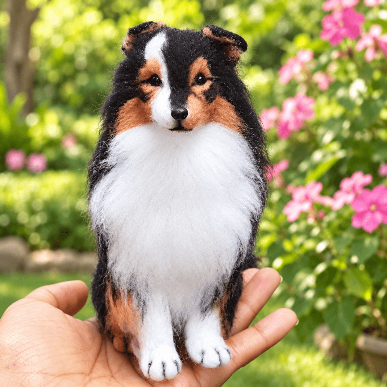 Tricolor Sheltie (Shetland Sheepdog) needle felted miniature dog portrait, front view, sitting on an open hand